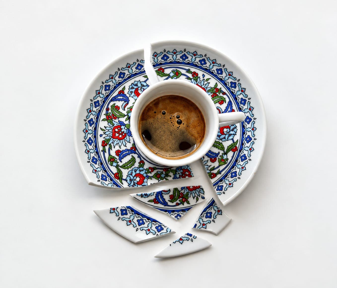 A broken patterned saucer pieced back together around a full cup of coffee